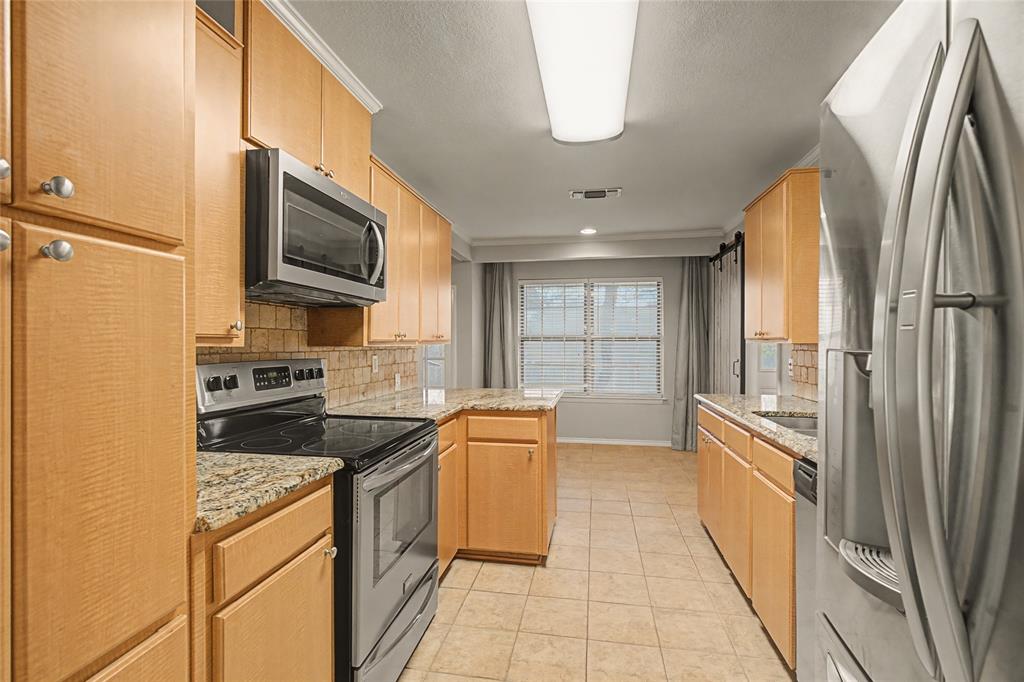 3200 Hickory Court Bedford, TX 76021 - Photo 7 of 30 Kitchen with stainless steel appliances, decorative backsplash, light stone counters, a peninsula, and light wood finish cabinets