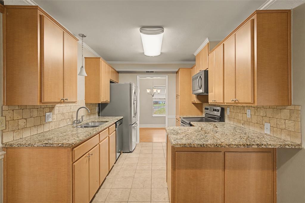 3200 Hickory Court Bedford, TX 76021 - Photo 8 of 30 Kitchen featuring decorative backsplash, stainless steel appliances, light stone countertops, a peninsula, and ornamental molding