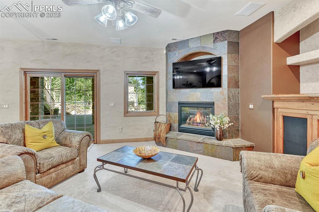17890 Queensmere Drive Monument, CO 80132 - Photo 26 of 50 a living room with furniture a fireplace and a flat screen tv