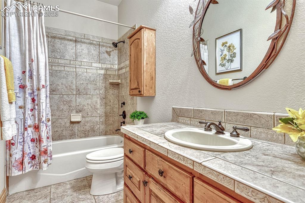 17890 Queensmere Drive Monument, CO 80132 - Photo 37 of 50 a bathroom with a granite countertop sink toilet a mirror a vanity and shower