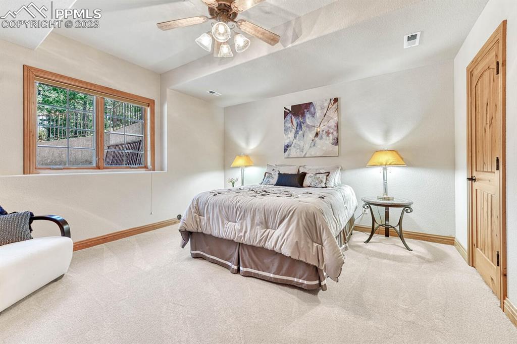 17890 Queensmere Drive Monument, CO 80132 - Photo 38 of 50 a spacious bedroom with a bed and a chandelier