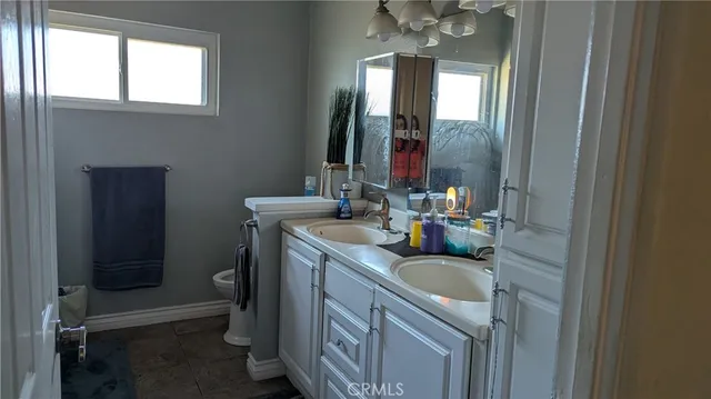 a bathroom with a sink vanity granite toilet and a mirror