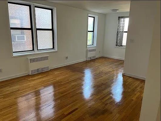 84-23 Manton Street, Unit 4A Queens, NY 11435 - Photo 5 of 18 an empty room with wooden floor and windows
