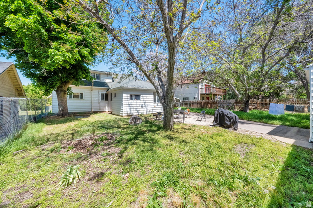 501 Canyon Road Ogden, UT 84404 - Photo 6 of 30 Expansive backyard featuring a mature tree, concrete patio area, and white siding on the rear of the residence