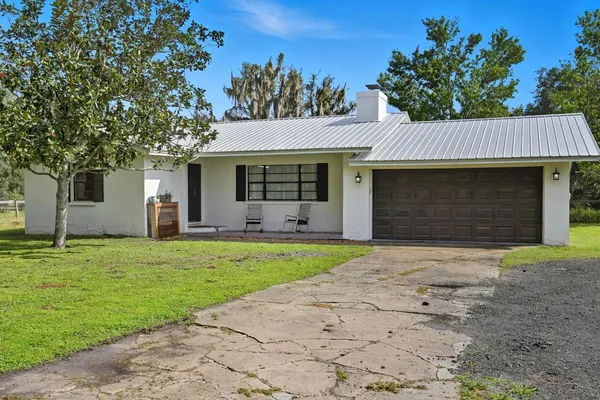 a front view of house with yard and trees in the background