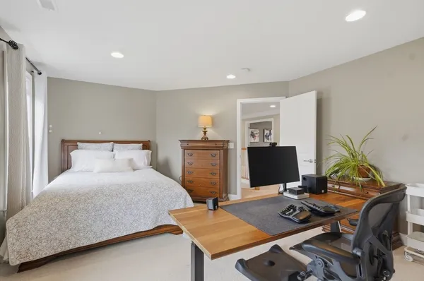 a bedroom with a bed and a computer on a desk next to a window