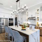 a kitchen with stainless steel appliances kitchen island granite countertop a dining table chairs and refrigerator