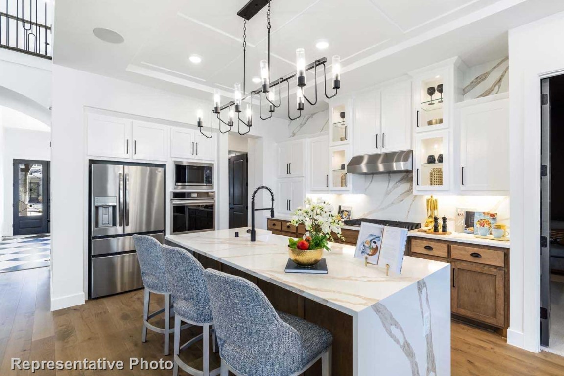a kitchen with stainless steel appliances kitchen island granite countertop a dining table chairs and refrigerator