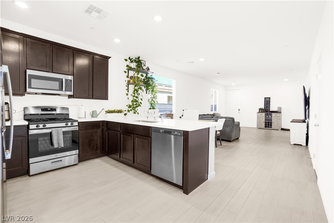 9398 Noble Fir Rdg Court Las Vegas, NV 89143 - Photo 11 of 36 A streamlined open-concept kitchen features stainless steel appliances and ample counter space, flowing into a bright living area.