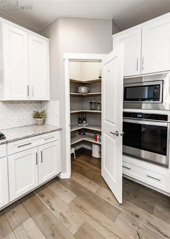 a open kitchen with stainless steel appliances granite countertop a stove a refrigerator a sink dishwasher a dining table and chairs with wooden floor