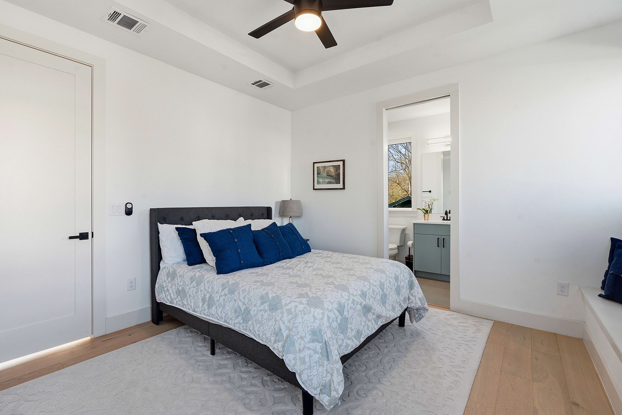 4313 Jinx Avenue, Unit 1 Austin, TX 78704 - Photo 22 of 40 Bedroom with light wood-style floors, a ceiling fan, a tray ceiling, and ensuite bath