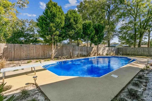 a view of a swimming pool with a patio and wooden fence