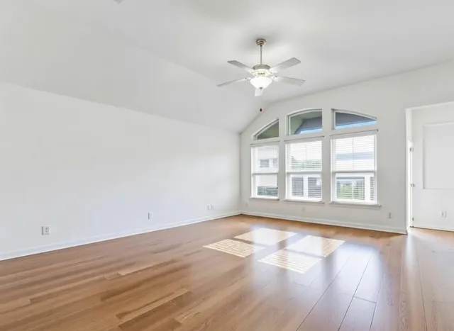a view of an empty room with wooden floor and a window
