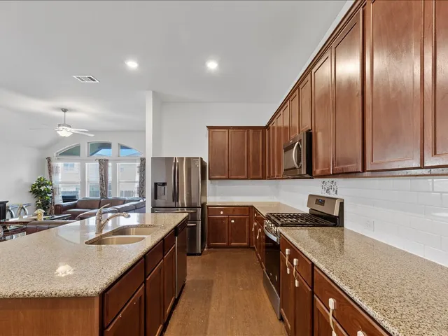a kitchen with stainless steel appliances granite countertop a sink a microwave a stove and a refrigerator