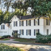 a front view of a house with a garden and tree