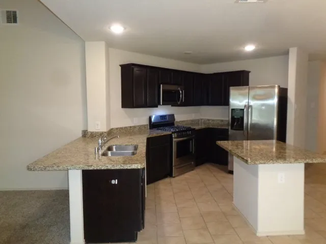 a kitchen with granite countertop a refrigerator and a stove top oven