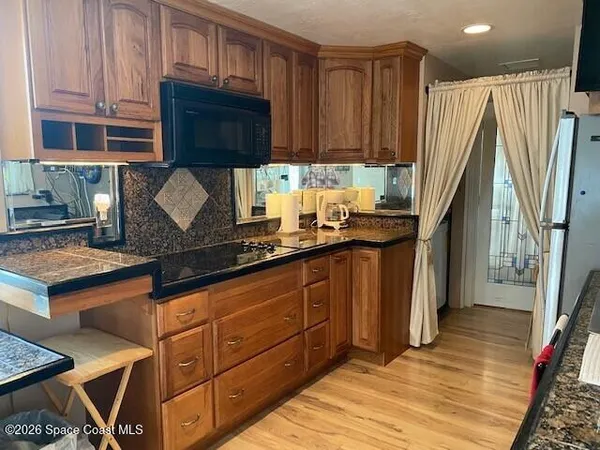 a kitchen with granite countertop a refrigerator a stove and wooden cabinets