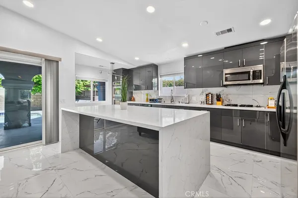 a kitchen with stainless steel appliances kitchen island granite countertop a refrigerator a sink a stove and oven