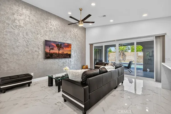a living room with furniture a flat screen tv and a floor to ceiling window