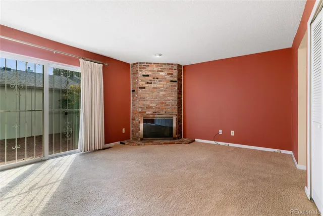 a view of an empty room with a fireplace and a window