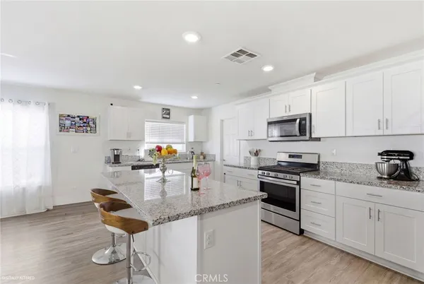 a kitchen with stainless steel appliances kitchen island granite countertop a sink cabinets and wooden floor