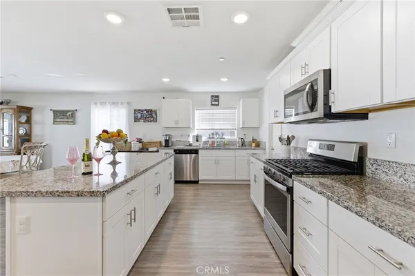 a large kitchen with stainless steel appliances granite countertop a stove sink and cabinets