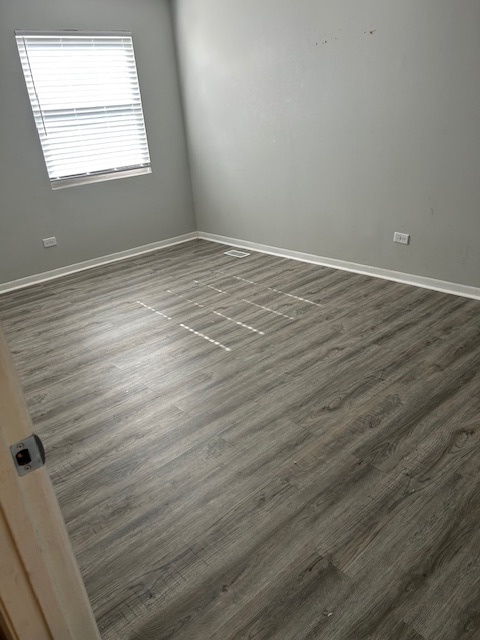 2186 North Oakbrook Circle, Unit 2186 Palatine, IL 60074 - Photo 7 of 11 an empty room with wooden floor and windows