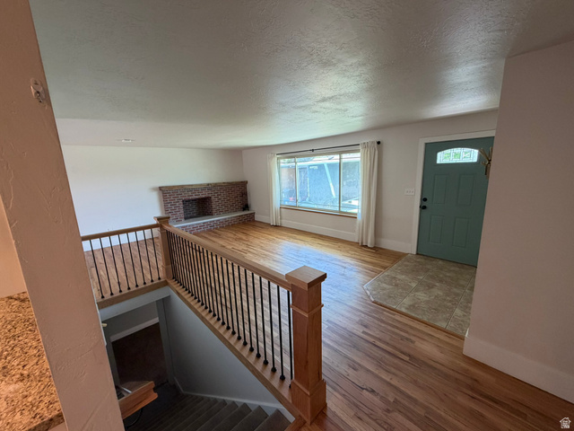 541 Mingo View Avenue Sandy, UT 84070 - Photo 2 of 16 Open-concept living area featuring wood-finish flooring, a brick fireplace, and a light blue entry door with decorative glass