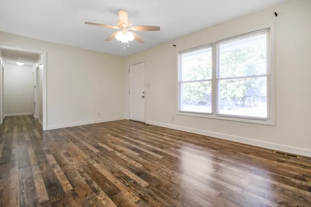 a view of empty room with wooden floor and fan