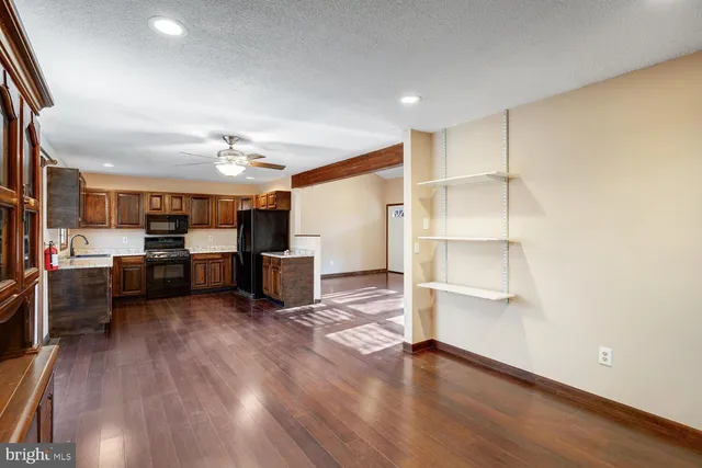 a living room with lots of wooden furniture and kitchen view