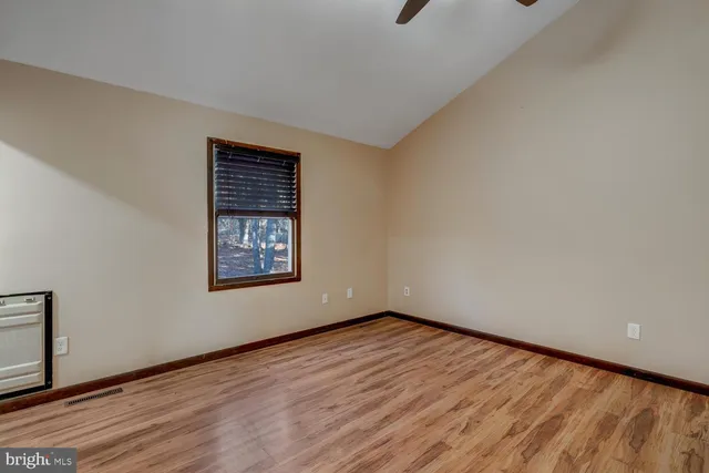 a view of an empty room with wooden floor and a window