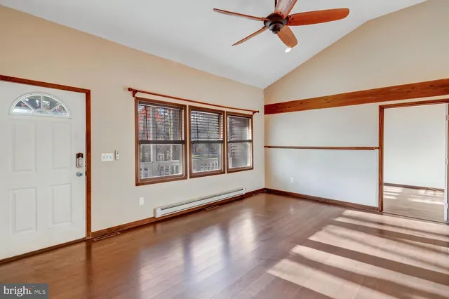 a view of an empty room with wooden floor and a window
