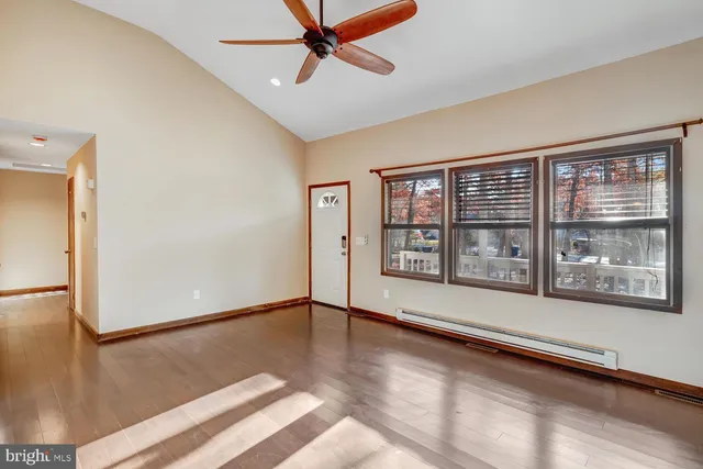 a view of an empty room with a window and wooden floor