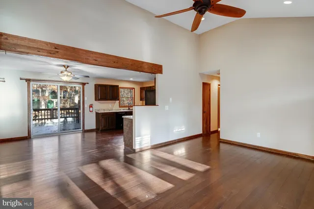 a view of a livingroom with wooden floor and a kitchen