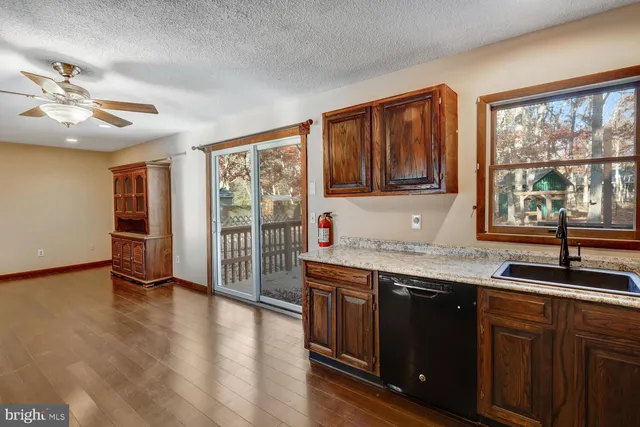 a kitchen with stainless steel appliances granite countertop a stove a sink and a refrigerator with wooden floor