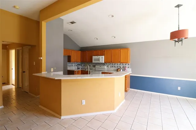 a large kitchen with stainless steel appliances a large counter top a stove a chimney a sink and a refrigerator