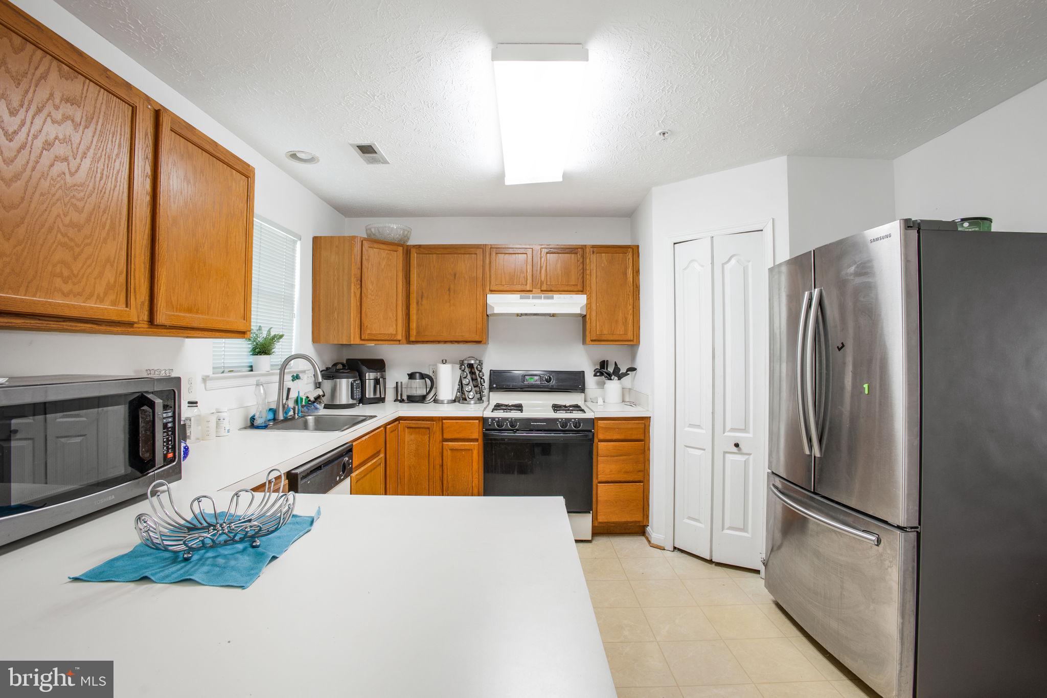 9820 Berrywood Court Bowie, MD 20721 - Photo 38 of 43 a kitchen with stainless steel appliances granite countertop a refrigerator a sink dishwasher a stove a washer and dryer with wooden floor