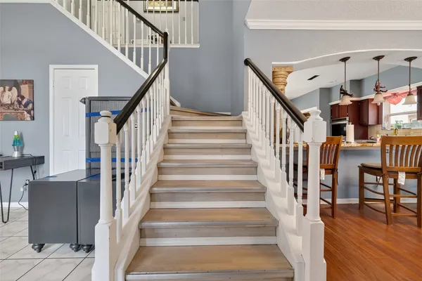 a view of staircase with lots of frames on wall and a dining table