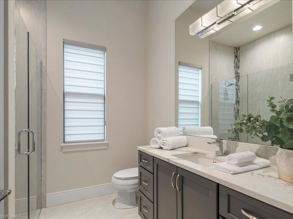 16337 Corsica Way Naples, FL 34110 - Photo 18 of 47 a bathroom with a granite countertop sink toilet and mirror