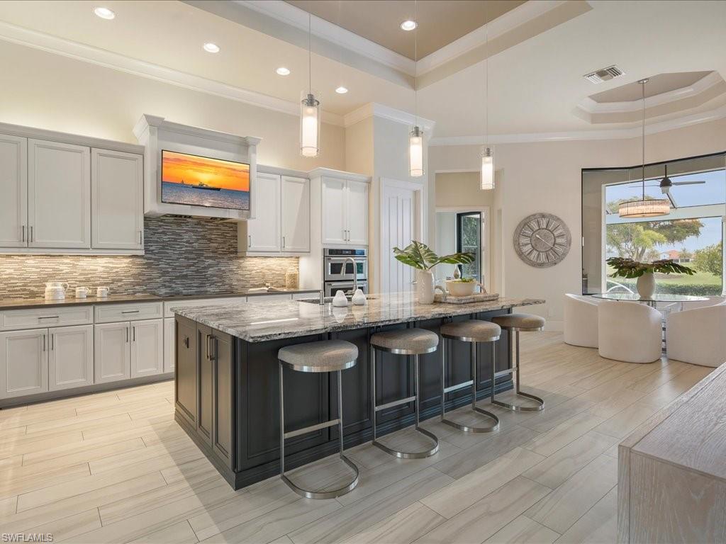 16337 Corsica Way Naples, FL 34110 - Photo 8 of 47 a kitchen with granite countertop a stove a sink dishwasher and cabinets with wooden floor