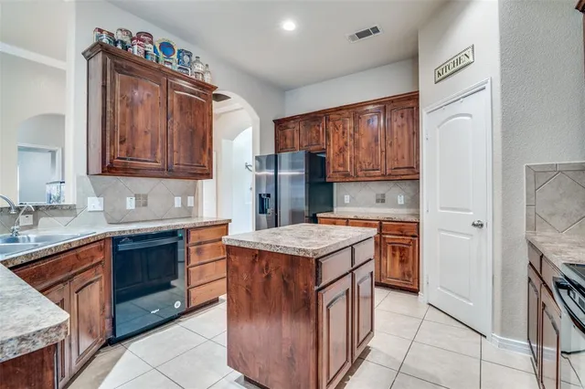 a kitchen with stainless steel appliances granite countertop a stove top oven a sink dishwasher and a refrigerator with wooden cabinets