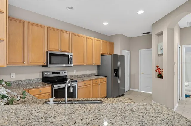 a kitchen with stainless steel appliances granite countertop a refrigerator stove top oven and sink