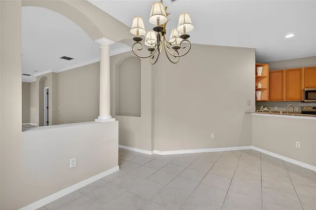 a view of an empty room with a chandelier and wooden floor