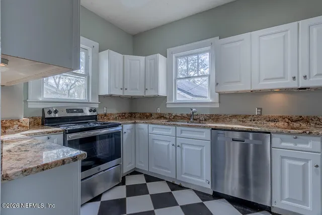 a kitchen with granite countertop white cabinets and appliances