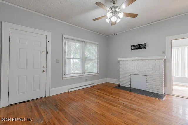 a view of empty room with wooden floor and fan