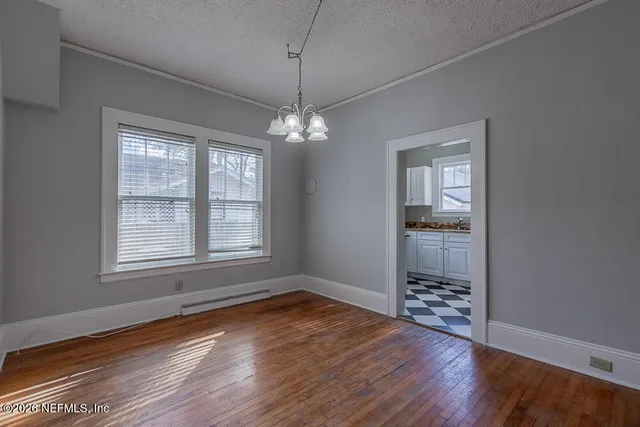 a big room with wooden floor a chandelier fan and windows