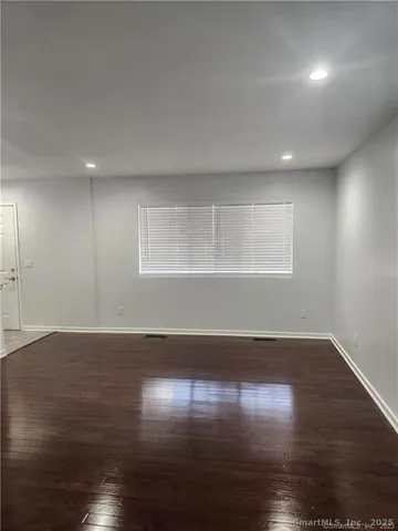 an empty room with wooden floor and windows with curtains