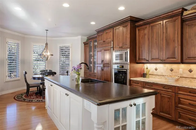 a kitchen with stainless steel appliances granite countertop a table chairs sink and cabinets