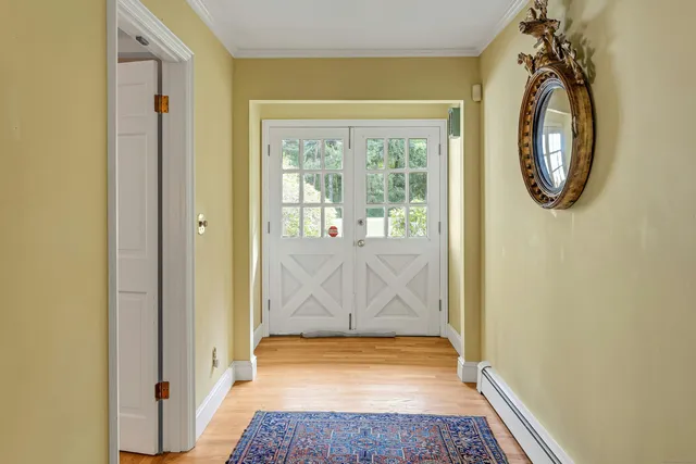 a view of a room that has a large window and wooden door