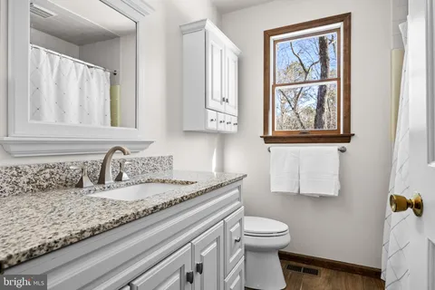 a bathroom with a granite countertop sink a toilet and mirror